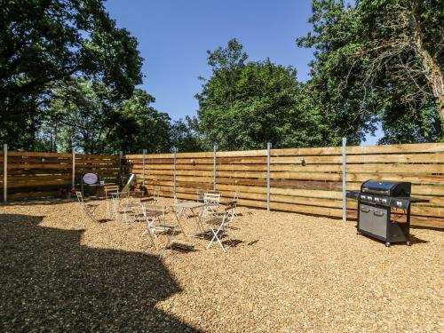a backyard with a fence and chairs and a grill at The Retreat at Glanrannell Park House in Llanwrda