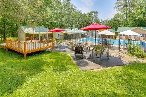 a patio with tables and umbrellas next to a pool at 6 Mi to Bethel Woods Cabin with Pool Access in Mongaup Valley