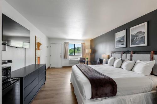 a bedroom with a large white bed and a kitchen at Adventure Inn Durango in Durango