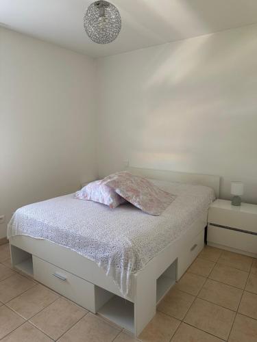 - une chambre blanche avec un lit et un oreiller dans l'établissement Appartement moderne en résidence avec piscine, à Mèze