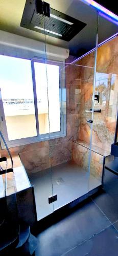 - une douche en verre dans une chambre avec fenêtre dans l'établissement Village Naturiste Cap d'Agde 224 Résidence de luxe Les jardins d'Eden 