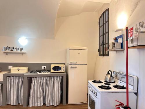 a kitchen with a white refrigerator and a stove at Palazzo D'Alessandro Wunderkammer & Suites B&B di charme in Caporciano
