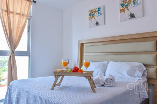 Una cama con una bandeja de fruta y dos copas de vino. en Volcano Views Apartment, en San Salvador