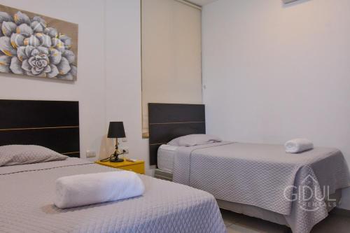 una camera da letto con due letti e un dipinto sul muro di Volcano Views Apartment a San Salvador