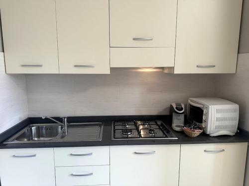 a kitchen with white cabinets and a stove and a microwave at Appartamento Paganini Modena in Modena