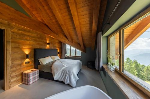 a bedroom with a bed and a large window at La Tana Lodge & SPA in La Colla