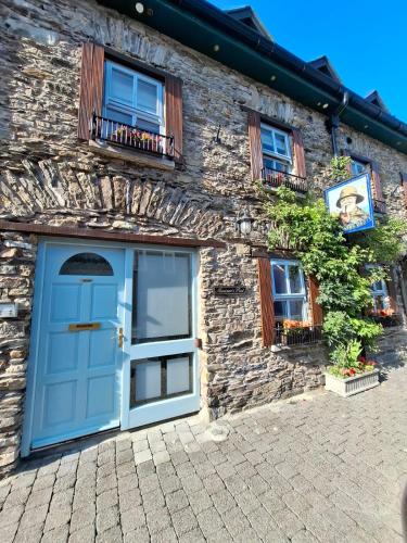 a stone house with a blue door and windows at Mariners Rest One Bedroom Apartment in Innishannon Village in Cork