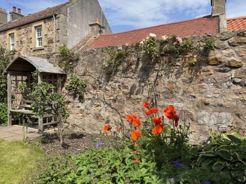 a stone wall with flowers in front of a building at Crab Shack, Crail in Crail