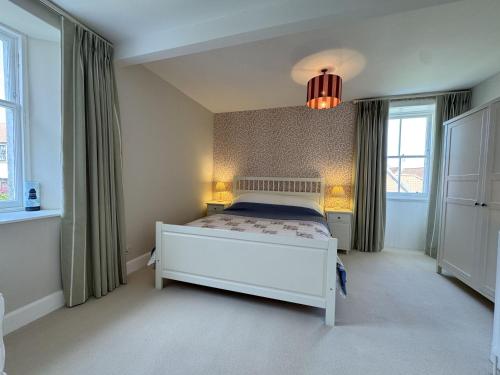 a bedroom with a white bed and two windows at Crab Shack, Crail in Crail