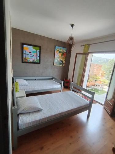 deux lits dans une chambre avec une fenêtre dans l'établissement Bas de villa, terrasse au calme, à Gattières