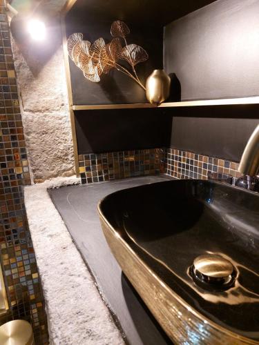 une salle de bain avec un lavabo noir et un miroir dans l'établissement La parenthèse Ponote - Hammam - WIFI - city center, au Puy-en-Velay