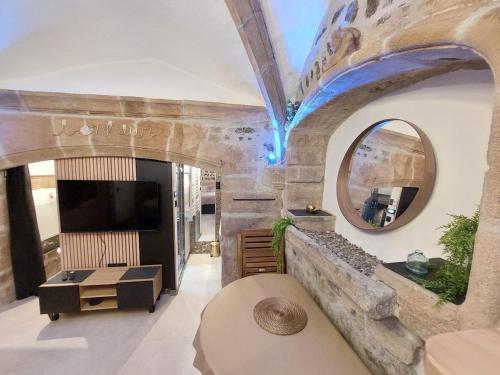 sala de estar con TV y pared de piedra. en La parenthèse Ponote - Hammam - WIFI - city center, en Le Puy en Velay