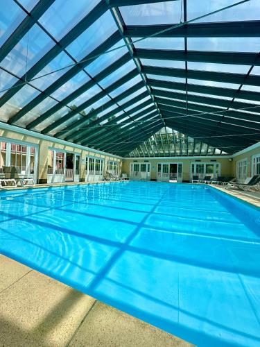 une grande piscine intérieure avec un plafond dans l'établissement Les Jardins d'Opale 1, à Le Touquet-Paris-Plage