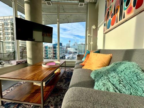 a living room with a couch and a table and a tv at InfinityNest Chic downtown escape stunning views in Calgary