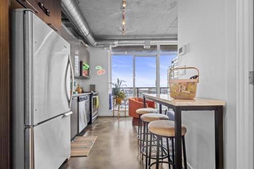 a kitchen with a refrigerator and a counter with stools at InfinityNest Chic downtown escape stunning views in Calgary