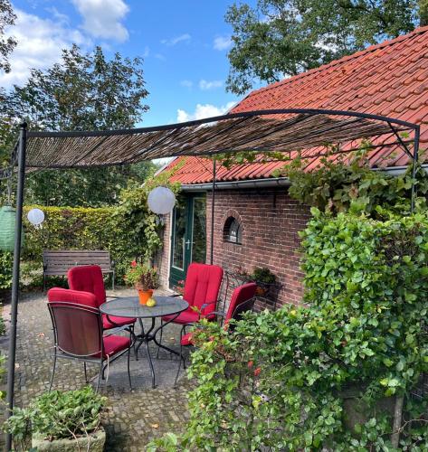 a patio with red chairs and a table and a building at Landelijk gelegen Huisje op erf in Veeningen