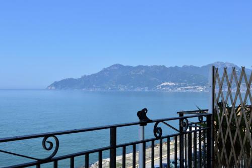 a person sitting on a fence near the water at B&B Fronte Del Mare in Salerno