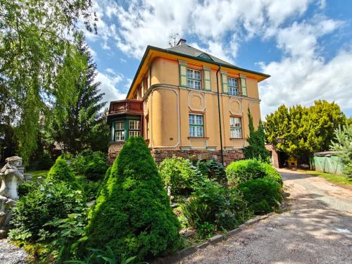 a yellow house with bushes in front of it at Vila Mezi Časy in Trutnov