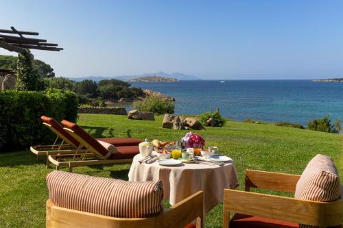 a table and chairs with a table and the ocean at Hotel Pitrizza, Costa Smeralda in Porto Cervo