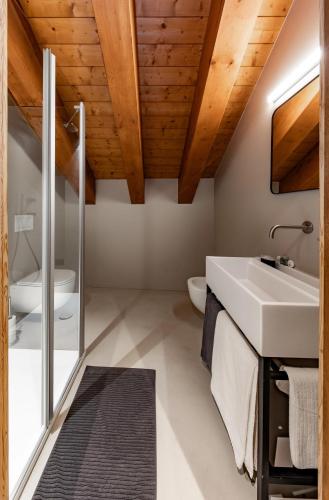 a bathroom with a white sink and wooden ceilings at La Tana Lodge & SPA in La Colla