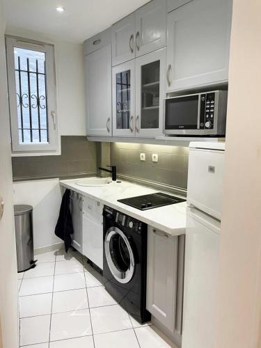 une cuisine avec un lave-linge et un micro-ondes dans l'établissement Appartement 75017 proche Parc Monceau, à Paris