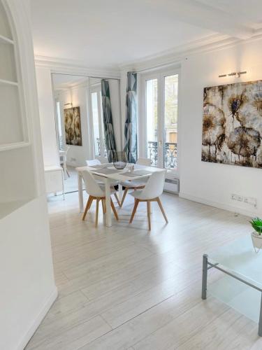 une salle à manger blanche avec une table et des chaises blanches dans l'établissement Appartement 75017 proche Parc Monceau, à Paris