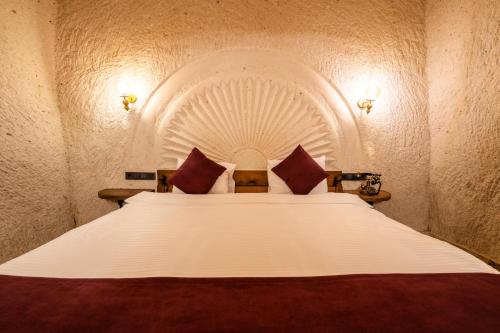 a bedroom with a large white bed with red pillows at Library Cave House in Urgup