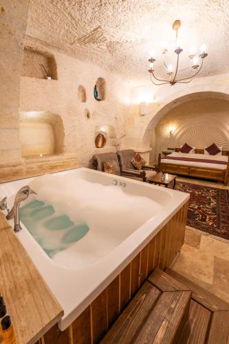 a large bath tub in a room with a bed at Library Cave House in Urgup