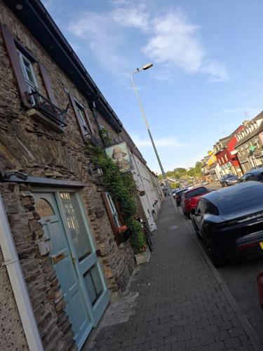 a stone building with a blue door on a street at Mariners Rest One Bedroom Apartment in Innishannon Village in Cork