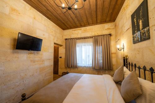 a bedroom with a bed and a tv on a wall at Library Cave House in Urgup
