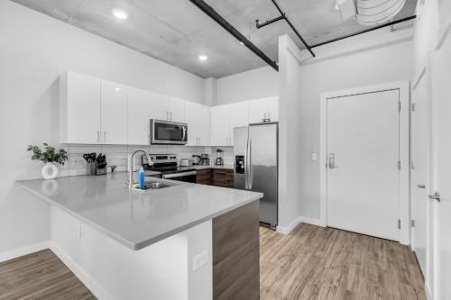 a kitchen with white cabinets and a stainless steel refrigerator at Chic 2BR Getaway Walk to Breweries and Art Walk in St Petersburg