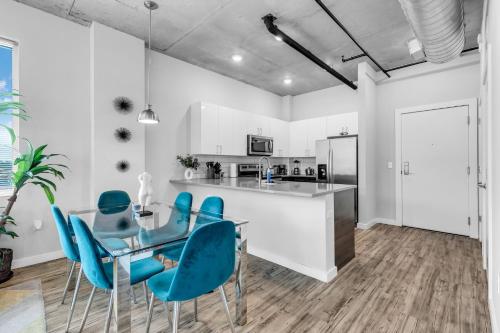 a kitchen with a glass table and blue chairs at Chic 2BR Getaway Walk to Breweries and Art Walk in St Petersburg