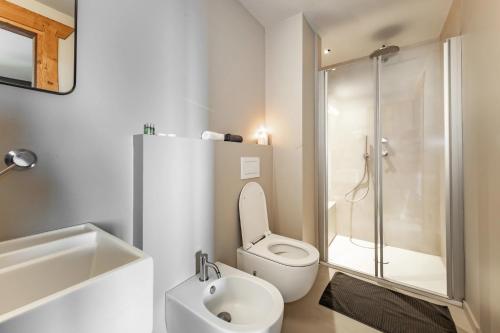 a white bathroom with a toilet and a shower at La Tana Lodge & SPA in La Colla