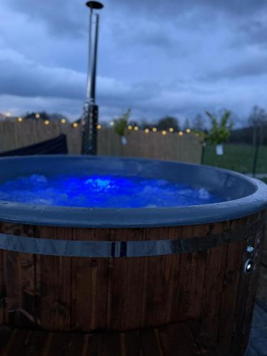 a hot tub with blue water in a wooden barrel at Makówka in Mysłakowice