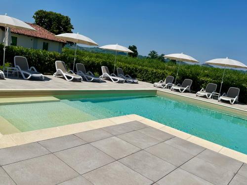 a swimming pool with lounge chairs and umbrellas at CASCINA SANT'ANTONIO in Alba