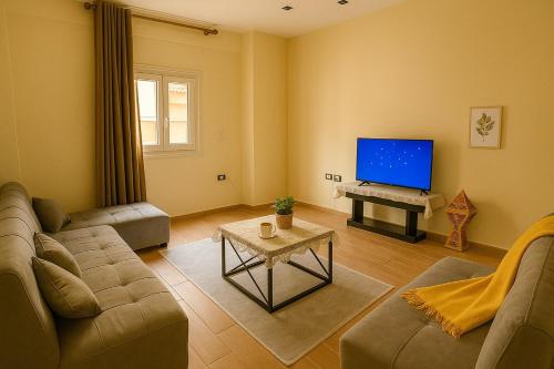 a living room with a couch and a flat screen tv at Stylish 2BR Flat - El Shorouk, Near Madinaty in Madīnat ash Shurūq