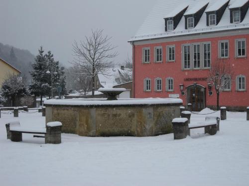 a snow covered courtyard with a fountain in front of a red building at Hotel Alte Posthalterei in Creuzburg