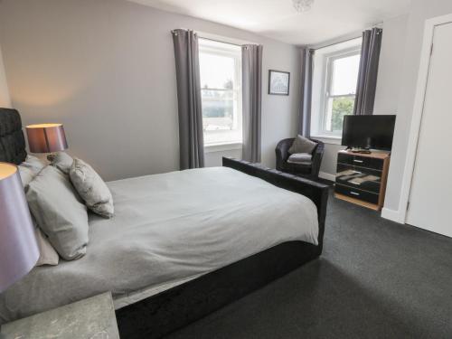 a bedroom with a large bed and a television at Fleet Townhouse in Castle Douglas
