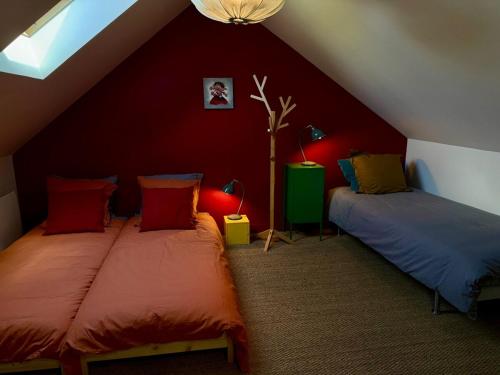 Cette chambre mansardée comprend 2 lits et des murs rouges. dans l'établissement Stylish countryside house, à Houssay