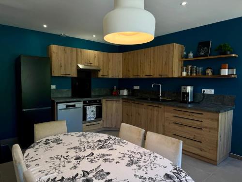 une cuisine avec une table et une cuisine aux murs bleus dans l'établissement Stylish countryside house, à Houssay