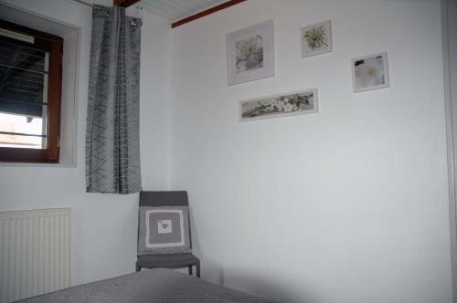 a bedroom with a chair and pictures on the wall at La Bardelière in Corbelin