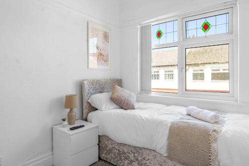 a white bedroom with a bed and a window at Contractor Stays, Newly Renovated, Free Parking, Sleep 7 in Wallasey