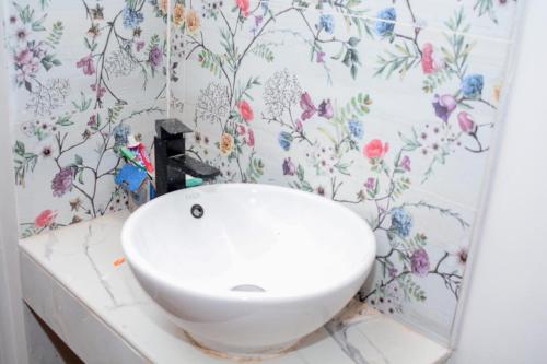 a white sink in a bathroom with floral wallpaper at Tropical lodge in Kakamega