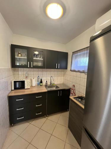 a kitchen with black cabinets and a stainless steel refrigerator at Gréta Apartman in Ábrahámhegy