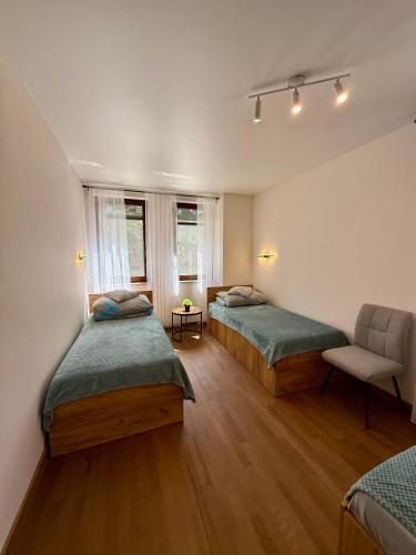 a room with two beds and a chair in it at Zajazd Stodoła sauna w cenie in Stronie Śląskie