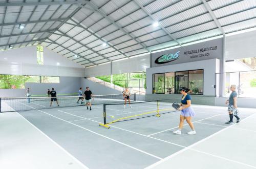 a group of people playing tennis in a tennis court at Castillo Colonial Nosara - by Pura Villas in Nosara