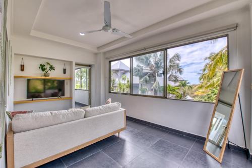 a living room with a couch and large windows at Castillo Colonial Nosara - by Pura Villas in Nosara