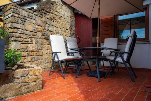 a patio with a table and chairs and a stone wall at Hiska Calla, pocitniska hisa z razgledi, blizu Pirana in Sečovlje