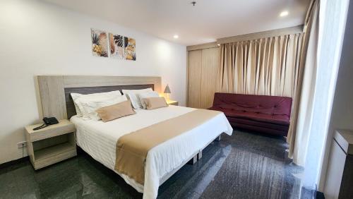 a bedroom with a large bed and a red couch at Hotel BE Suites Cali in Cali