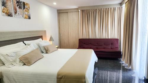 a bedroom with a large bed and a red chair at Hotel BE Suites Cali in Cali